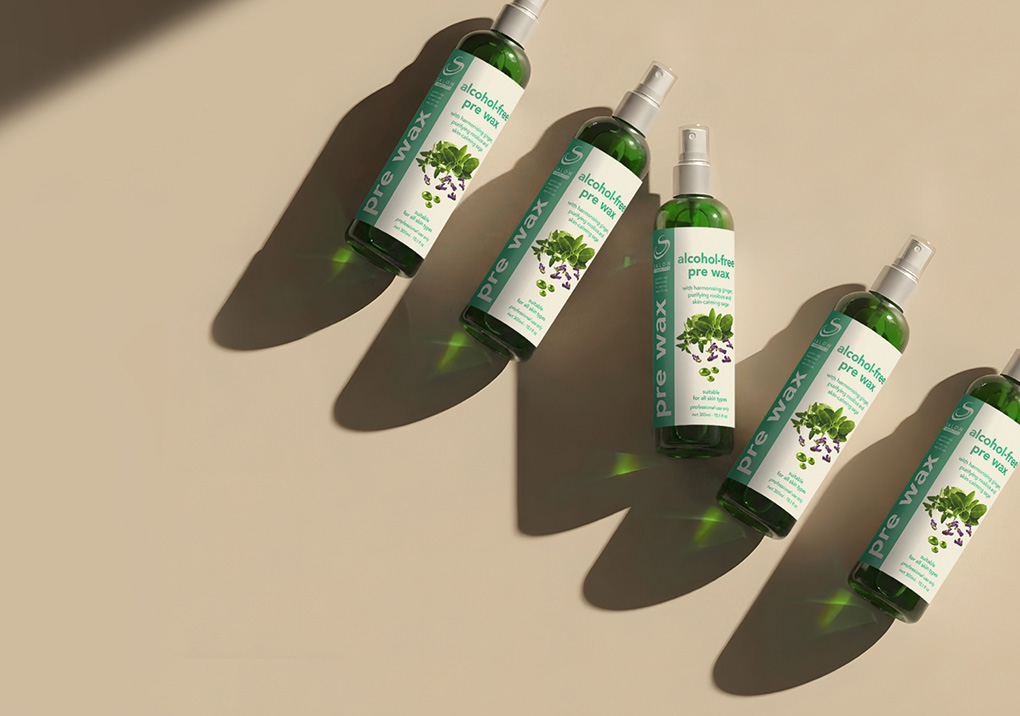 Six bottles of alcohol-free pre-wax spray arranged diagonally on a beige surface, labels showing 'alcohol-free pre wax' with a mint illustration and long shadows.